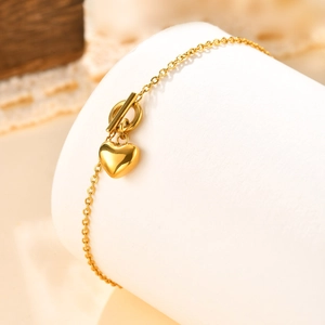 Détail du bracelet cœur plaqué or 18 carats avec fermoir à bascule sur support blanc