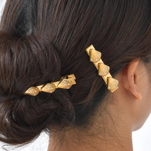 Close-up of golden shell hair clips with rhinestones worn on hair for a stylish look