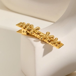 Macro detail of golden flower hair clip with five petals on a polished metal base