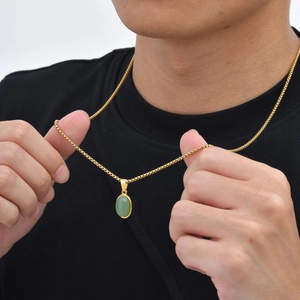 Macro-opname van een vintage herenketting met groene ovale steen en gouden ketting