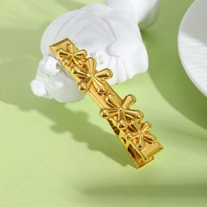 Golden stainless steel hair clip featuring four 3D floral accents on a smooth metal base
