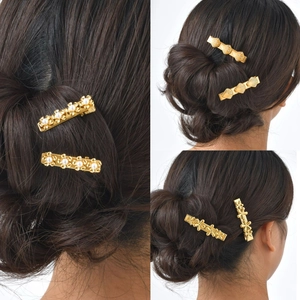 Set of three golden flower and shell hair clips with pearls on dark hair styling
