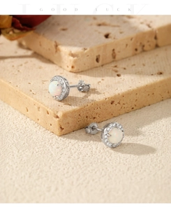 Close-up of S925 sterling silver earrings with round white opal and diamond halo