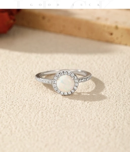 Macro detail of S925 silver ring featuring a round opal with vibrant fire and crystal accents