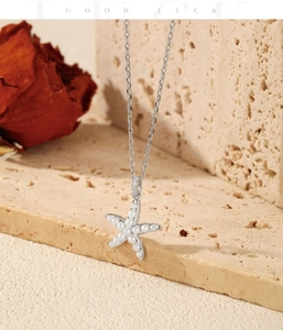 Macro shot of silver starfish necklace with gradient pearls on a textured stone base