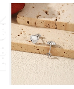 Close-up of heart-shaped S925 silver studs with tiny crystals on a stone surface