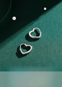 Macro detail of polished 925 sterling silver heart earrings on dark green background