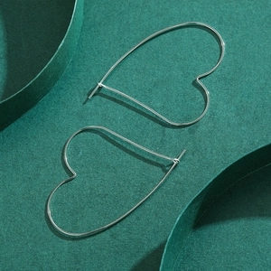 Boucles d'oreilles cœur en argent minimalistes sur fond vert foncé de qualité supérieure