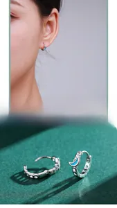 Detail of S925 silver hoop earrings with blue enamel moon and cubic zirconia