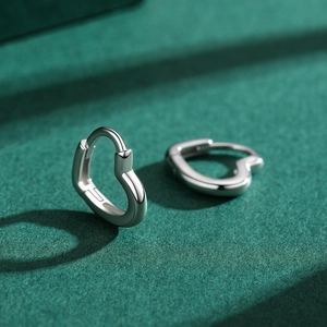 Minimalist S925 sterling silver heart hoop earrings with polished finish on green surface
