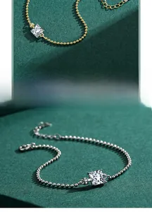Gros plan de bracelets à billes dorés et argentés avec un zircon carré central