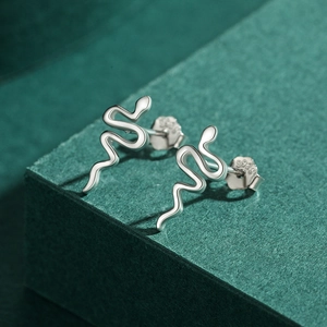 Minimalist S925 sterling silver snake stud earrings with polished finish on green background
