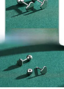 Détail de boucles d'oreilles cœur en argent 925 avec fermoir à vis et poinçon sur vert