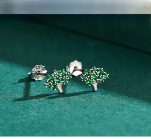 Macro view of S925 sterling silver tree stud earrings with pavé green gemstones