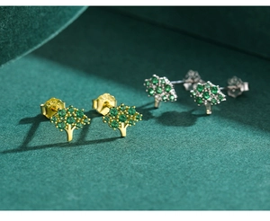 Macro shot of S925 silver tree earrings with green gemstones on green velvet background