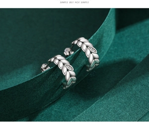 Detail of s925 silver leaf hoop earrings with micro zircon stones on green paper