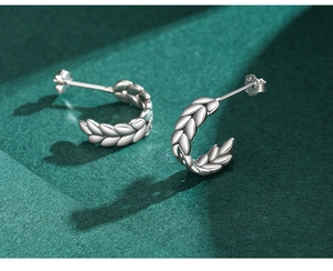Macro view of S925 sterling silver leaf stud earrings with high-polish metallic texture