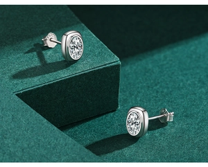 Detail of oval-cut zircon earrings in S925 sterling silver with bezel setting on green velvet