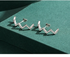 Detailed macro view of S925 sterling silver wave stud earrings with micro-set zircon stones