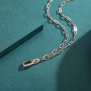Rose gold rectangular link necklace with micro-pave zircons on a dark green background