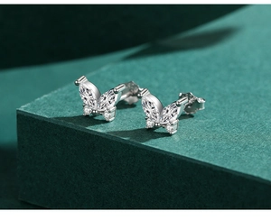 Vue macro des boucles d'oreilles papillon avec pierres de zircon sur support vert