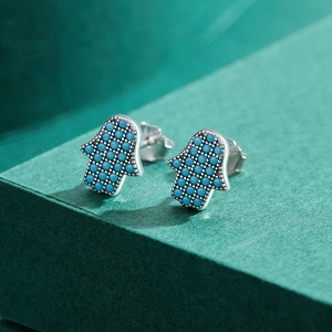 925 silver Hamsa Hand stud earrings with turquoise pavé setting on a green display