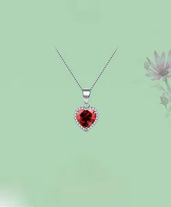 Détail macro du pendentif cœur en argent avec grand zircon rouge facetté et pierres blanches