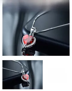 Détail macro d'un collier cœur en argent avec zircon rouge et halo de diamants