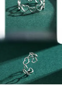 Macro detail of S925 sterling silver hollow heart open ring on dark green background