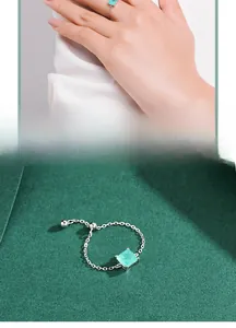 Detail of adjustable silver chain ring featuring a square Paraiba-style turquoise gemstone