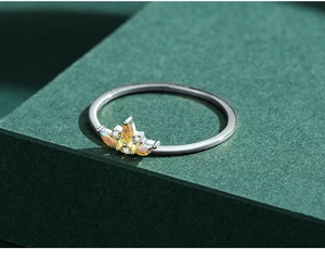 Gros plan d'une bague couronne en argent avec pierre marquise orange sur un socle