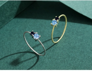 Close-up of S925 silver and gold rings with blue zircons and twisted rope design