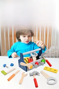 Toddler playing with wooden tool box set featuring colorful screws, wrench and hammer