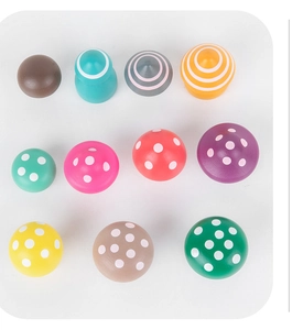 Top view of eleven colorful wooden mushroom toys with stripes and polka dots on white background