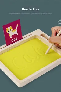 Enfant écrivant chat sur plateau de sable en bois avec stylet et carte alphabet