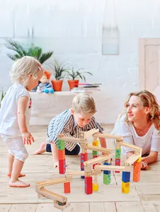 Family playing with colorful wooden marble run blocks on light wooden floor in home setting