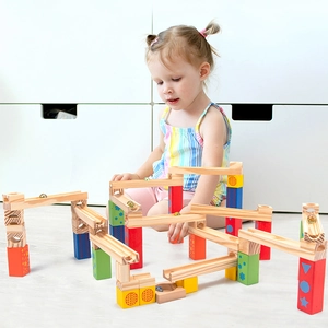 Child playing with colorful wooden marble run blocks set on a modern indoor floor