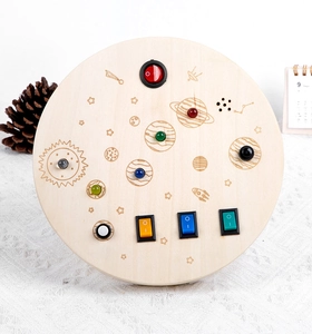 Close-up of wooden space-themed busy board with colorful LED buttons and toggle switches