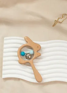 Detail of wooden rabbit rattle toy with colorful beads and bell for baby sensory play