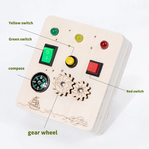 Close-up of wooden busy board with colorful LED switches, gears and a compass