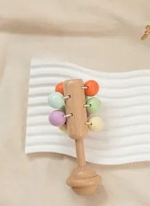 Macro detail of a grape-shaped wooden baby rattle with colorful macaron beads on a tray