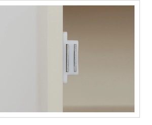 Close-up of white magnetic cabinet door catch installed on wooden kitchen furniture