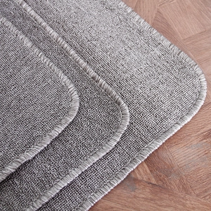 Thick grey Montessori work rug with granular texture and reinforced edges on wood floor