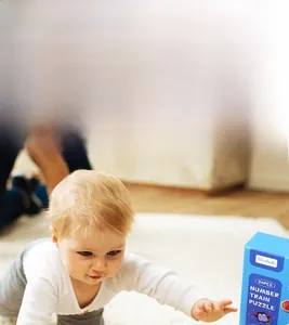 Toddler playing with number train matching puzzle on a soft white carpet for early learning