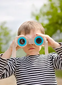 Bimbo che usa un binocolo in legno portatile con dettagli blu in un ambiente all'aperto
