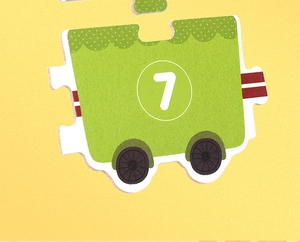 Close-up of green wooden train puzzle piece featuring the number seven for kids