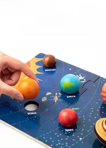 Close-up of hand placing colorful wooden planet pieces on a solar system puzzle board