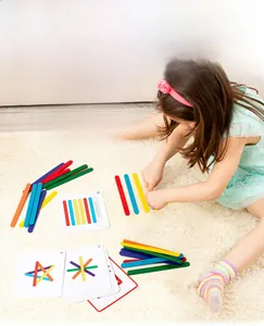 Kid playing with colorful wooden counting sticks and logic cards on a soft carpet