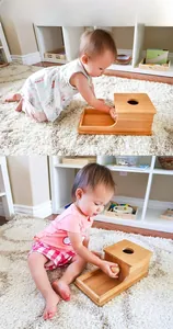 Montessori wooden object permanence box showing baby hand coordination training in a home setting