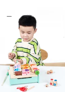 Detail of child playing with wooden toy barbecue set featuring colorful pretend food pieces